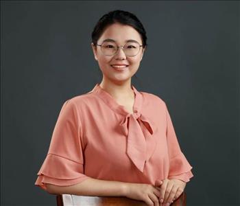 photo of a female employee with pink shirt in front of black background